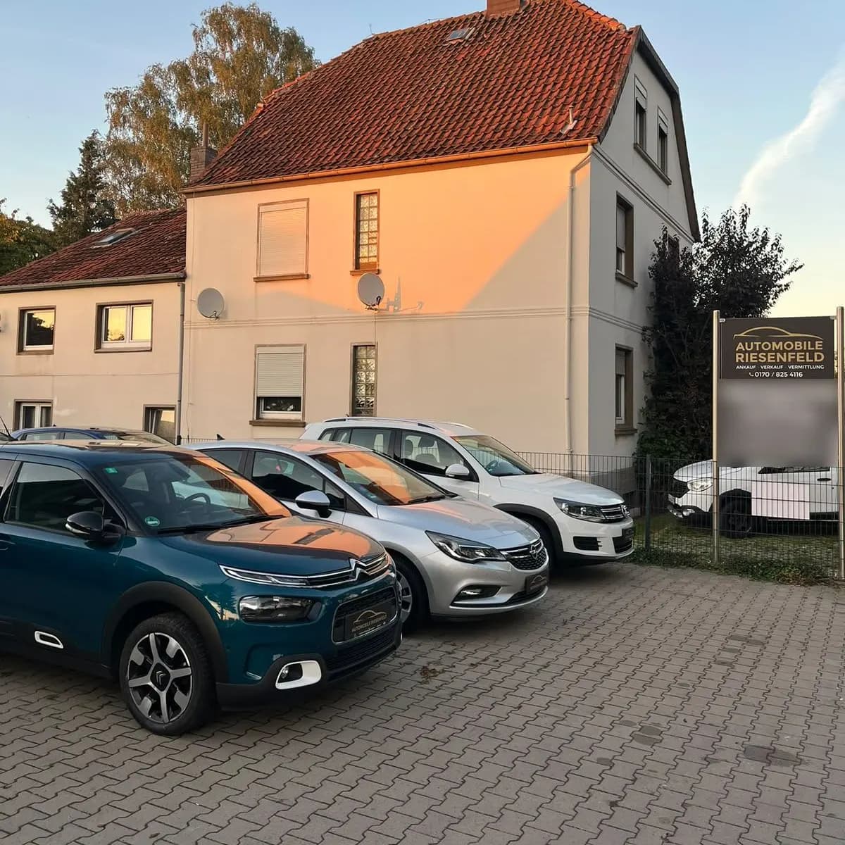 Gebrauchtwagen vor unserem Firmenschild im Abendlicht